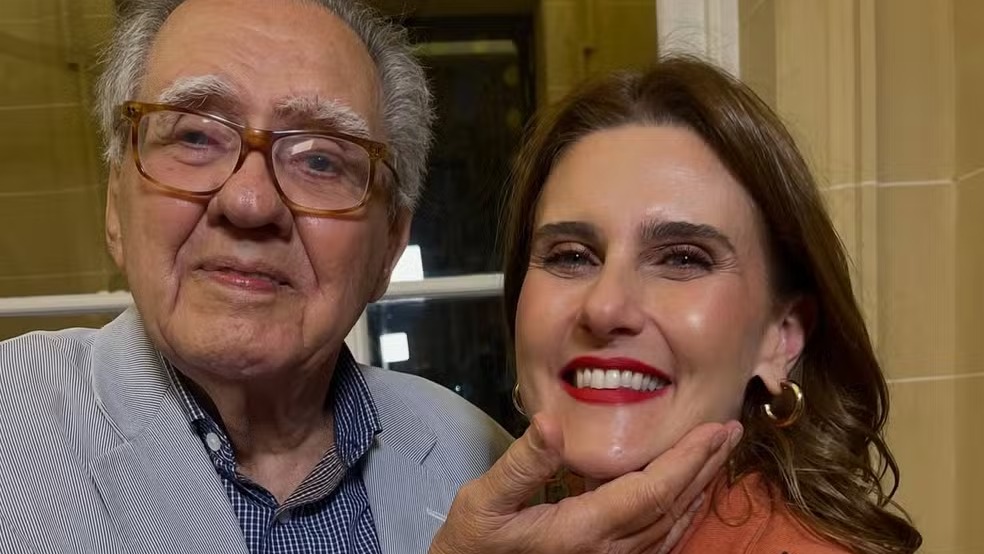 Jornalista Simone Zuccolotto e Luiz Carlos Barreto em foto compartilhada nas redes sociais. Foto: Reprodução/Instagram Close-up de homem idoso de óculos segurando queixo de mulher, ambos sorrindo para a câmera