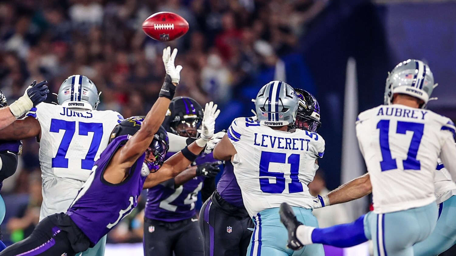 Lances acirrados marcaram a vitória do Baltimore Ravens sobre o Dallas Cowboys na estreia da NFL no Brasil. Jogadores do Dallas Cowboys e Baltimore Ravens disputando bola aérea, um jogador roxo tenta bloquear