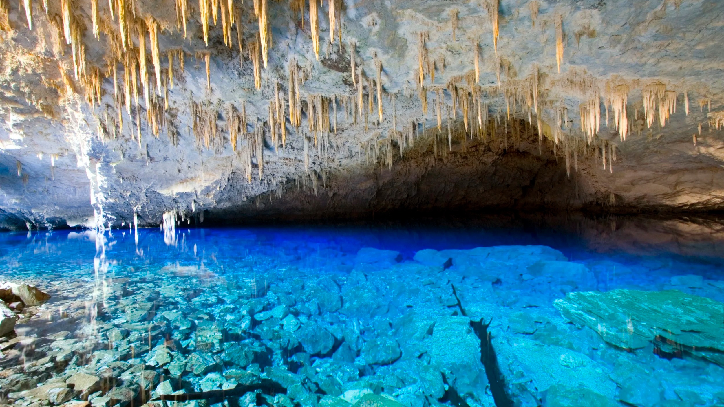 A Gruta do Lago Azul, em Bonito, ilustra a riqueza natural que consolida o Mato Grosso do Sul como destino de ecoturismo. Foto: Divulgação/Prefeitura de Bonito Gruta subterrânea com lago de água azul intenso e cristalina, e estalactites no teto.