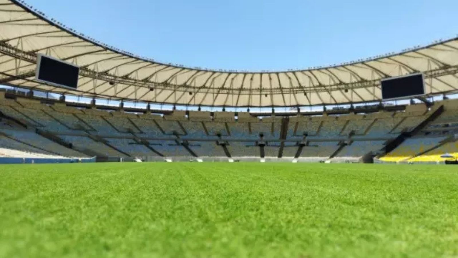 O Maracanã, palco da primeira partida da NFL no Brasil, preparado para o confronto histórico. Campo de futebol gramado e arquibancadas vazias do Estádio do Maracanã sob céu claro