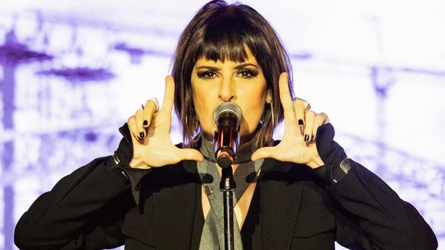 Fernanda Abreu é uma das atrações confirmadas para o MIMO Festival, parte da programação da Semana de Arte do Rio. Cantora com cabelo escuro e franja, segurando microfone com as mãos à frente em palco