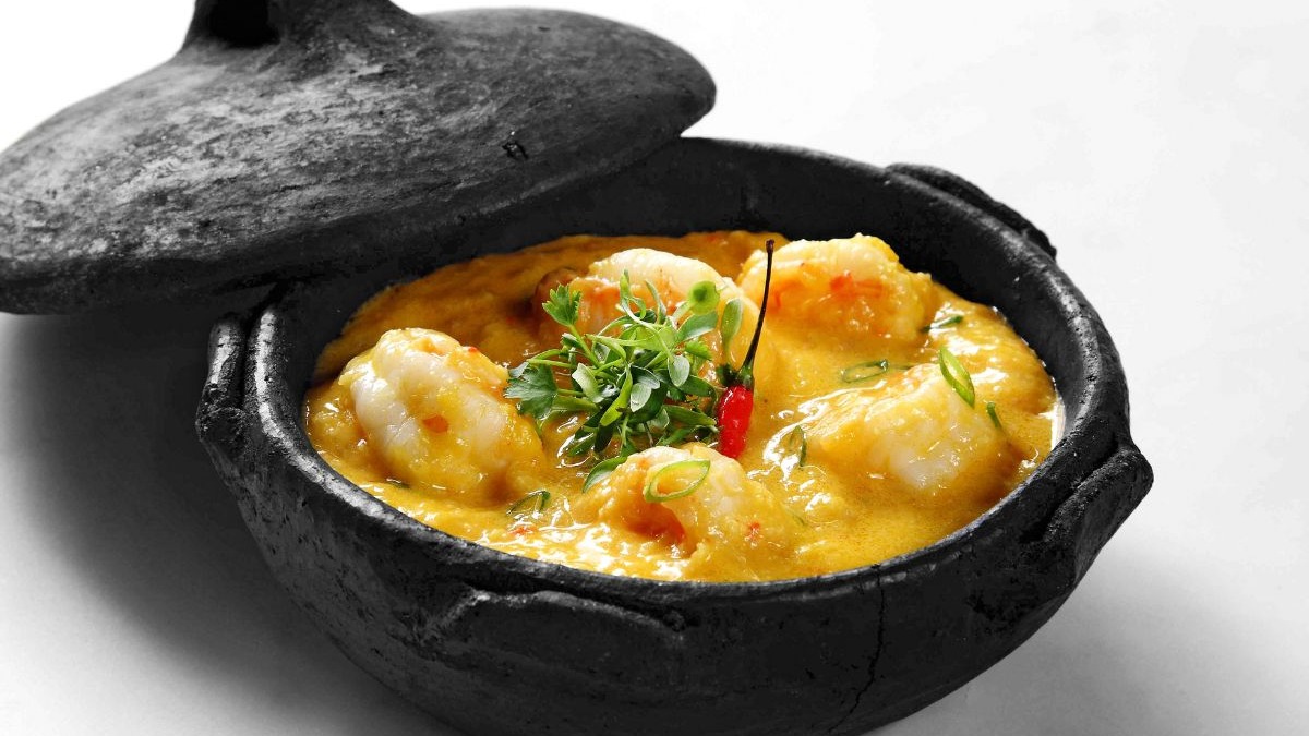 A moqueca, um clássico da culinária baiana, é a pedida certa para aquecer e confortar nos dias mais frescos de Salvador. Moqueca cremosa de camarão em panela de barro escura com coentro e pimenta vermelha.