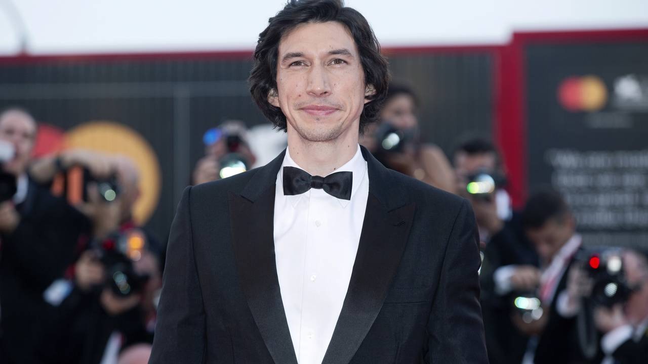 O ator Adam Driver, confirmado como Mister Sinister no MCU, durante evento de gala no tapete vermelho. Adam Driver sorrindo, vestindo smoking preto, camisa branca e gravata borboleta preta