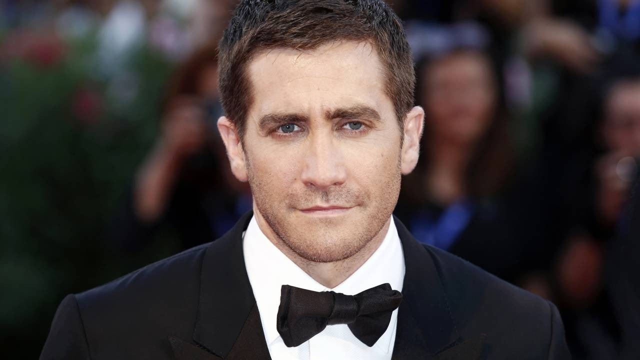 Jake Gyllenhaal, aclamado por "A Última Confissão", foi surpreendentemente esnobado pela Academia no Oscar 2026. Jake Gyllenhaal, em close, usa terno preto, camisa branca e gravata borboleta.