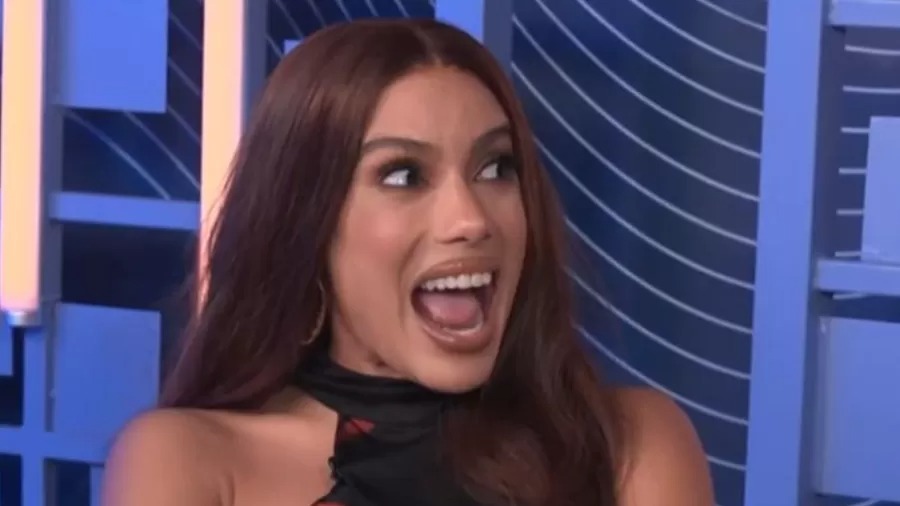 Anitta durante o programa. Mulher com cabelo castanho, boca aberta em reação, olhos olhando para o lado direito