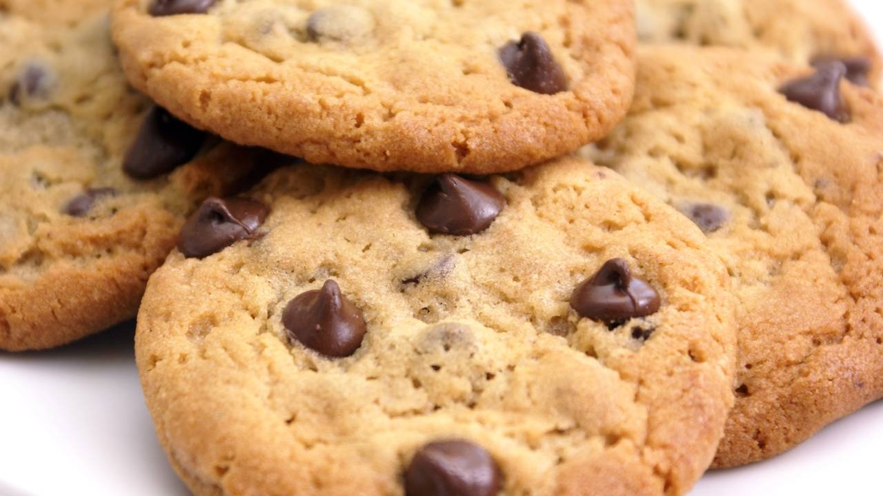 Nossa receita detalhada garante o cookie americano perfeito, com o equilíbrio ideal entre crocância e maciez. Vários cookies de chocolate com gotas de chocolate em um fundo branco