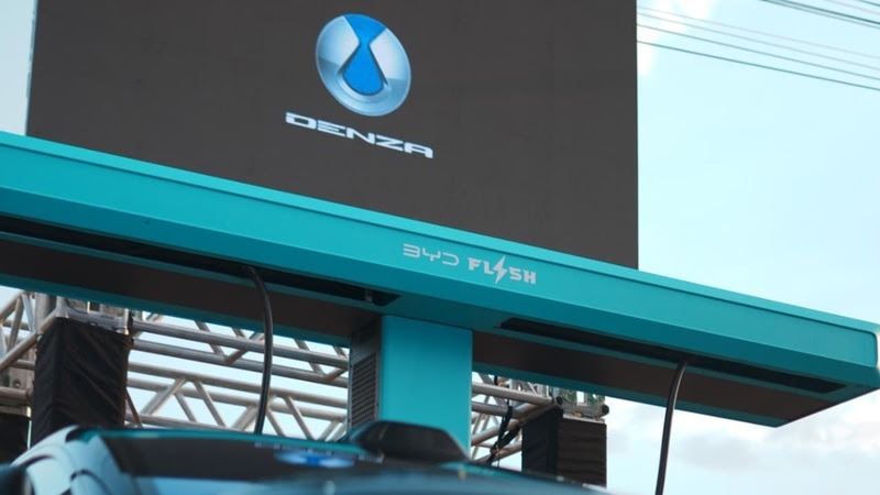 Unidade de carregamento azul BYD Flash com s&iacute;mbolo de raio, abaixo de tela preta com logo e texto Denza