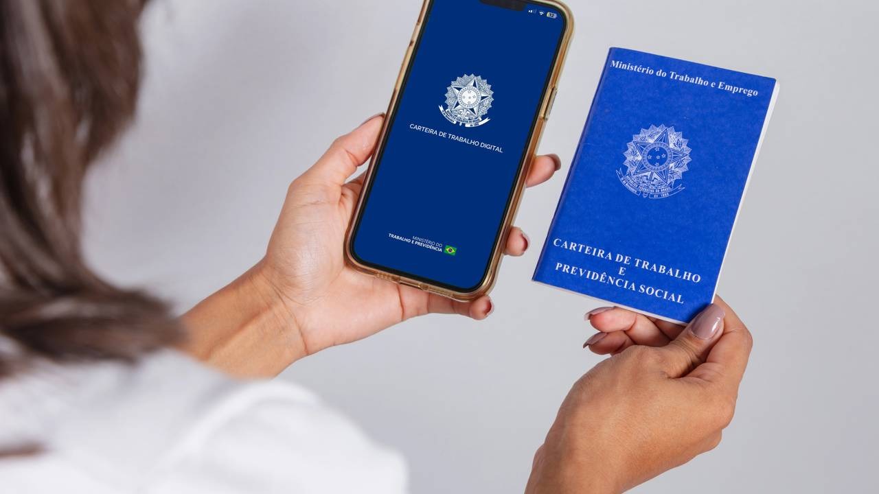 Carteira de Trabalho, física e digital, simboliza direitos trabalhistas e previdenciários, impactados pelo salário mínimo. Mãos seguram smartphone exibindo Carteira de Trabalho Digital e documento físico azul