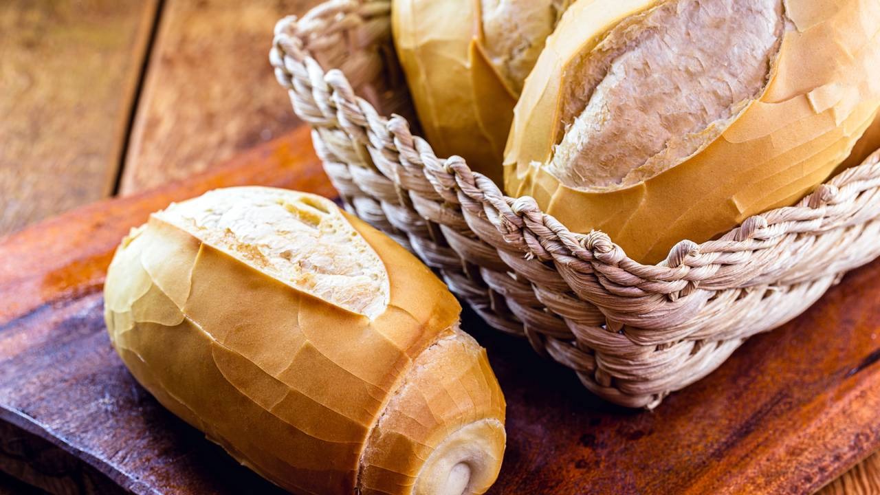 O pão francês, queridinho no café da manhã, pode ser um vilão para a saúde, segundo especialistas. Pães franceses em cesto de vime e sobre tábua de madeira
