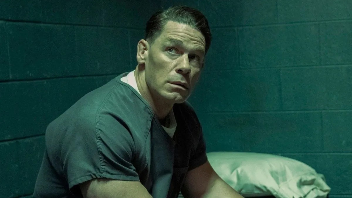 O anti-herói Pacificador, interpretado por John Cena, estrela uma das séries para quem busca outras opções no streaming. John Cena sério, em uniforme verde de prisão, olhando para cima em cela escura.