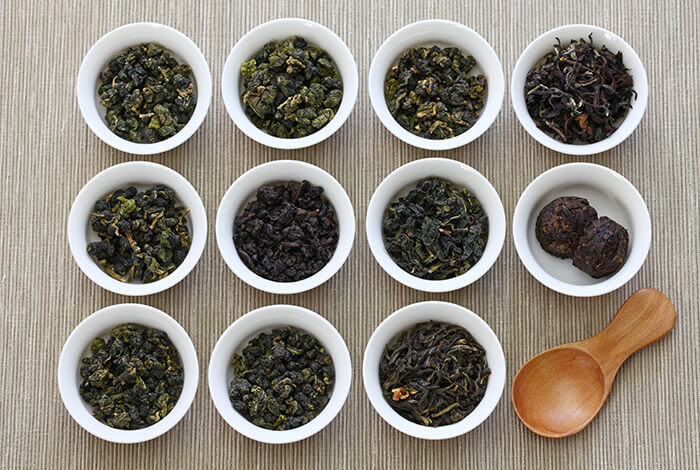 Different variety of tea leaves in small bowls.