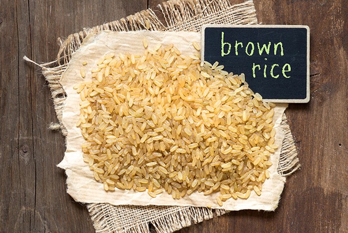 Uncooked brown rice placed on top of a piece of burlap.