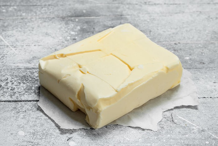 A bar of butter placed on a wooden surface.