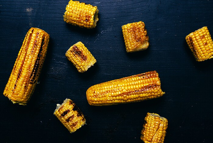 Pieces of grilled corn scattered on a smooth surface.