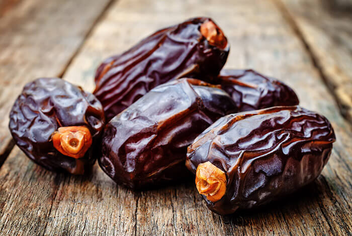 A closeup look of dried dates placed on a wooden surface.