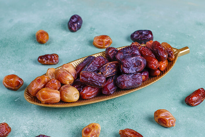 Different types of dried dates on a metal plate.