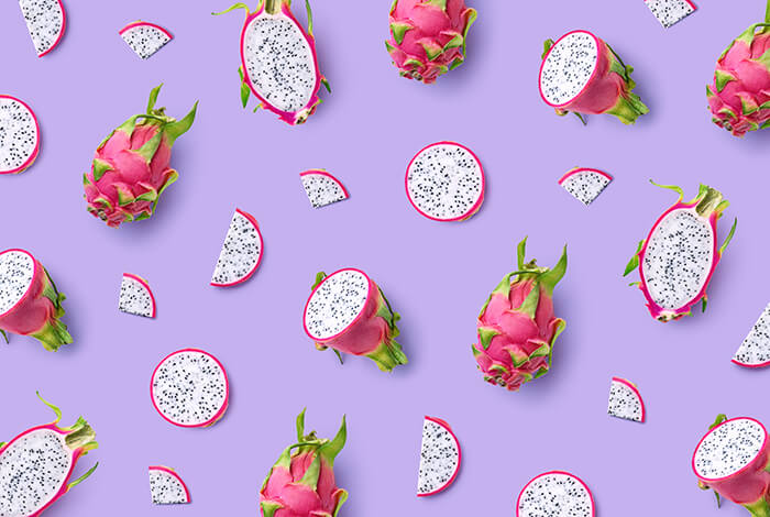 Dragonfruits and their slices scattered on a surface.