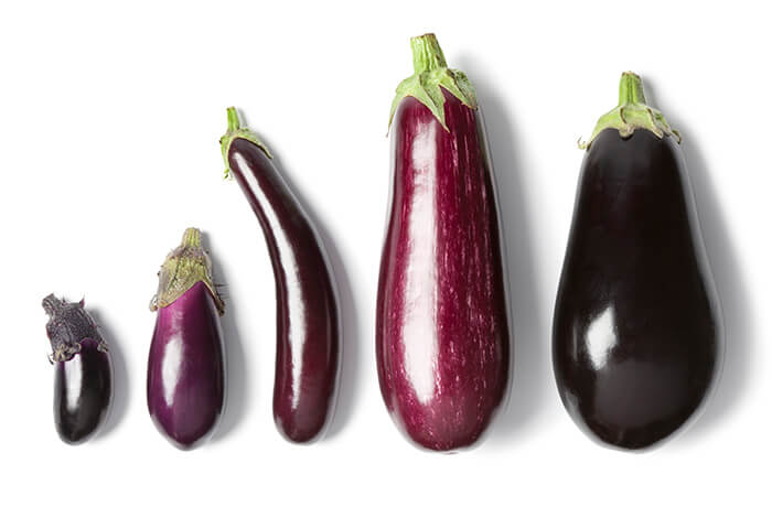 Different types of eggplants on a white surface. 