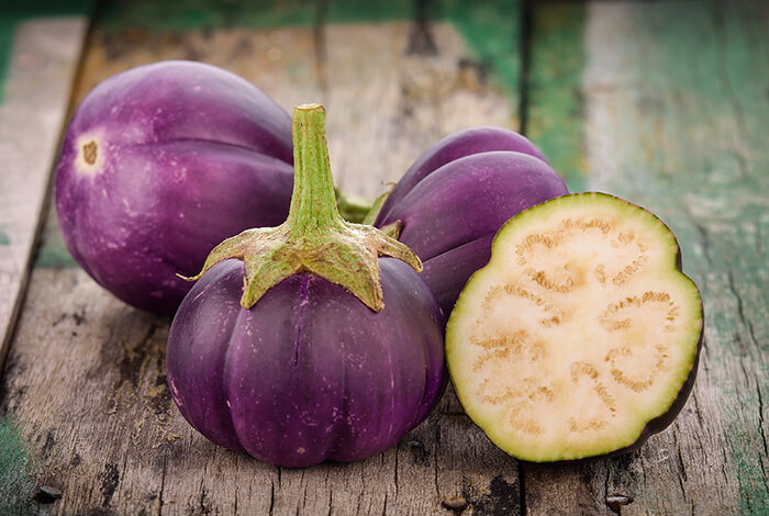 Raw eggplants on a wooden surface.