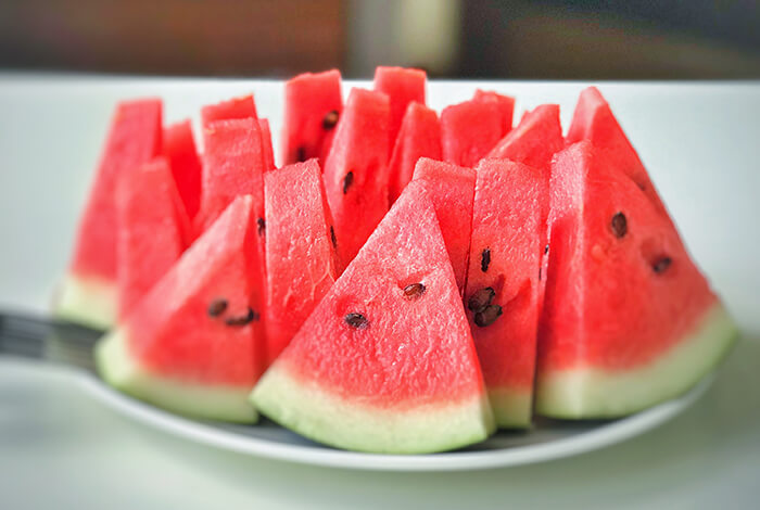 Slices of watermelon displayed on a white plate.