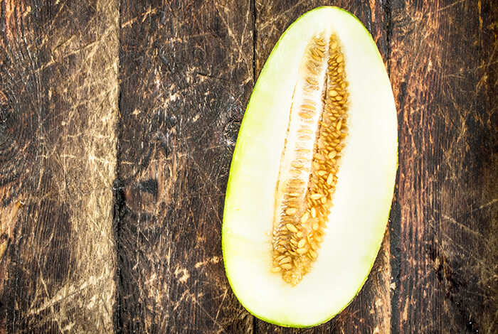 A melon sliced in half and its seeds are shown.