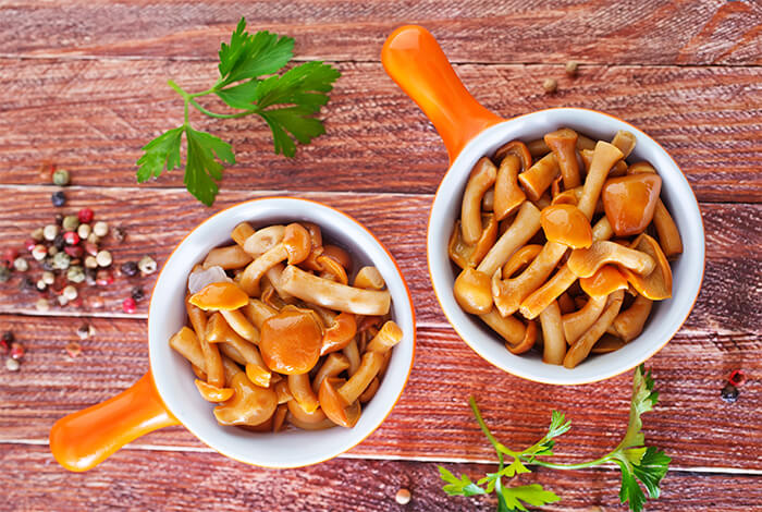 Two bowls filled with cooked mushrooms. 