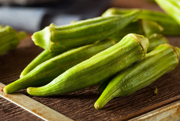 Pieces of raw okra on a wooden surface.