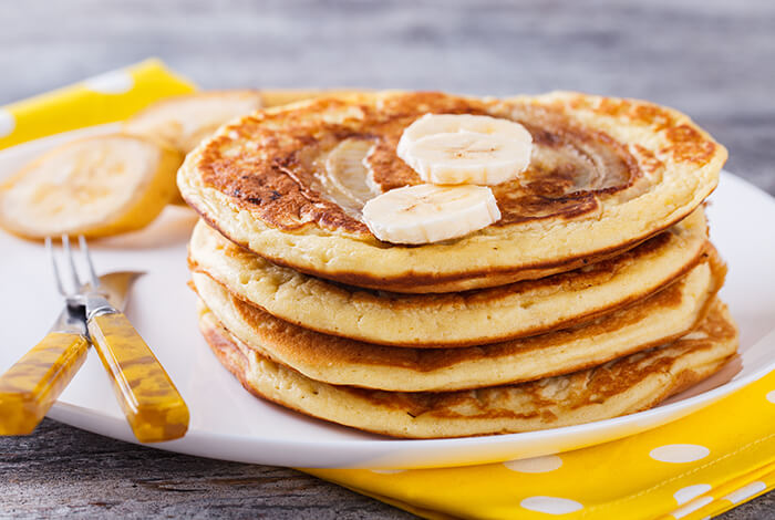 A stack of pancakes topped with sliced bananas.