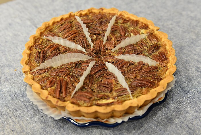 A pecan pie placed on a ceramic plate.