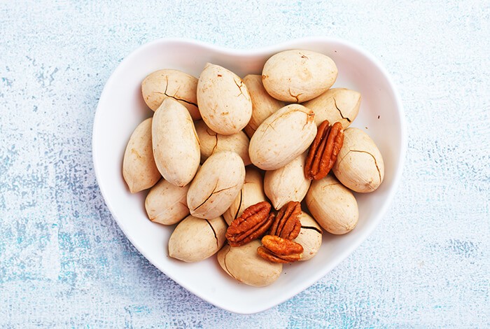 A heart-shaped bowl filled with pecans.