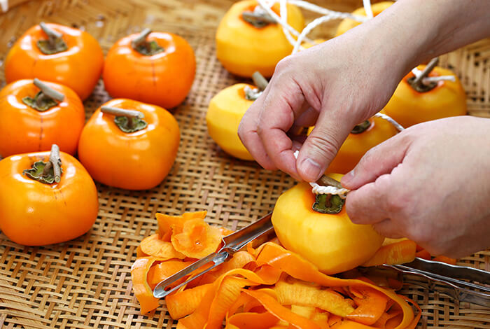 A person is peeling pieces of persimmons.