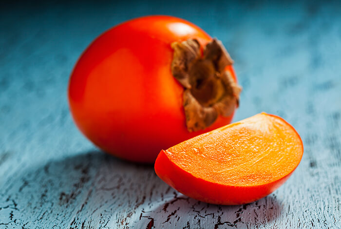 A sliced persimmon on a wooden surface.