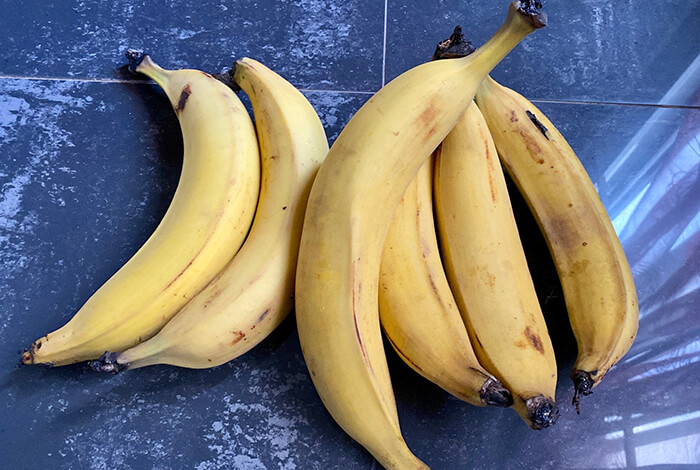 A bunch of yellow plantains on a tiled surface.
