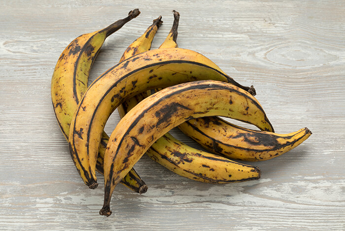 A bunch of sweet plantains on a wooden surface.
