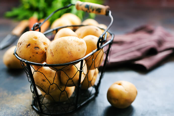 A basket filled with raw potatoes. 