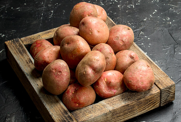 A wooden tray filled with red potatoes.