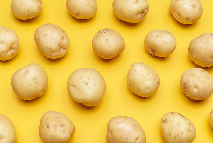 Pieces of raw potatoes on a yellow background. 