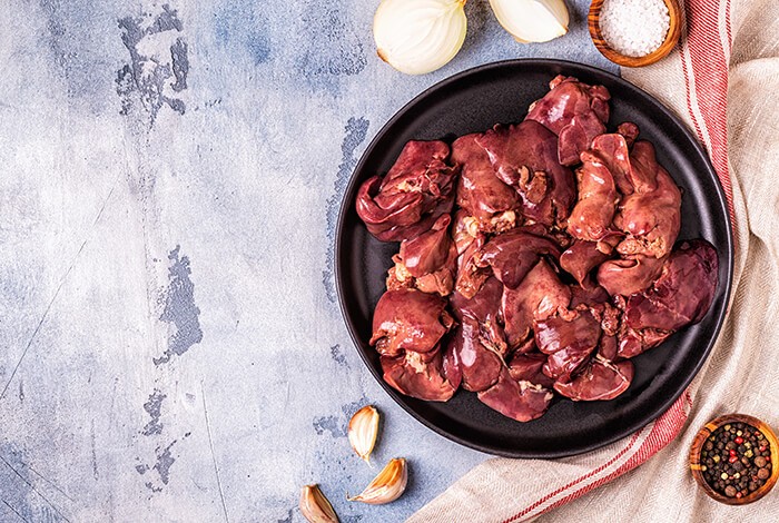 Seasoned chicken livers surrounded by seasoning ingredients.