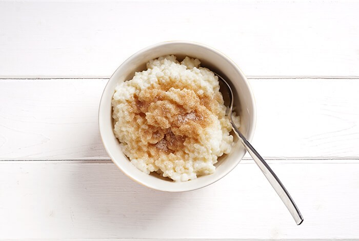 A bowl of rice pudding sprinkled with brown sugar.