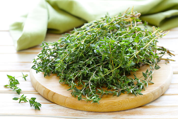 Sprigs of thyme on top of a round chopping board.