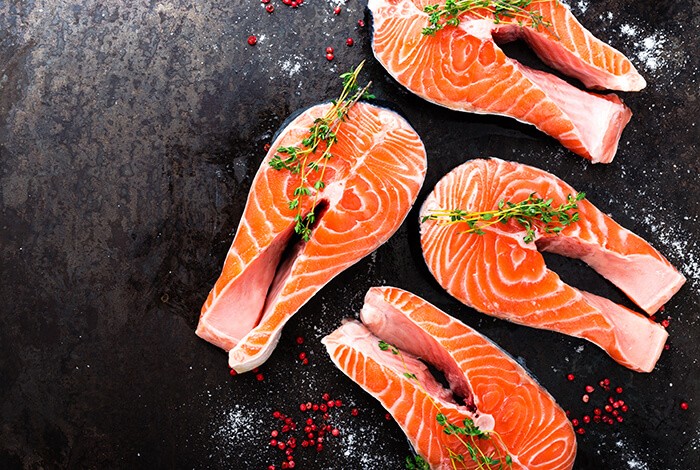 A few pieces of sliced salmon seasoned with different herbs.