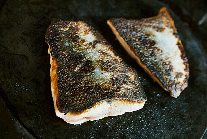 Seared salmon on an iron skillet.