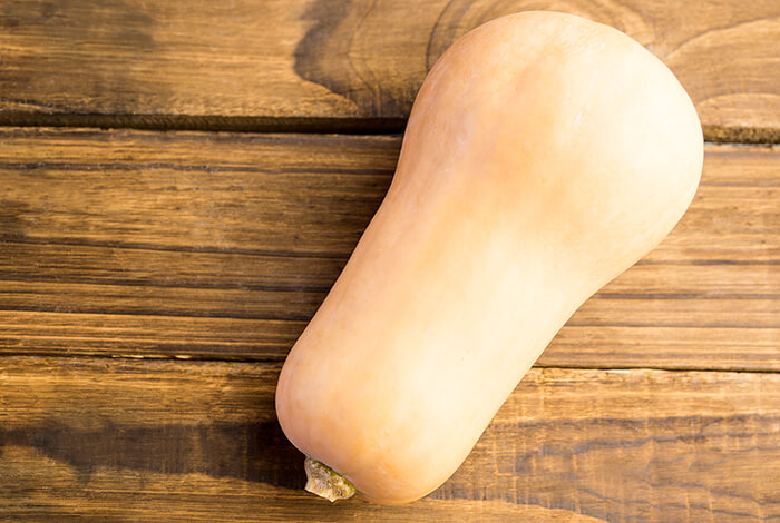 A big butternut squash displayed on a wooden surface.