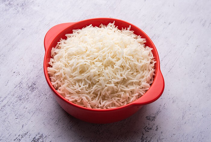 Cooked long-grain white rice placed in a red bowl.