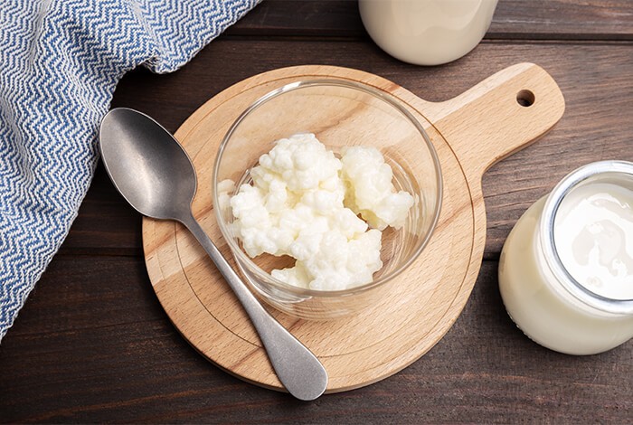 Curdled yogurt in a glass bowl and fresh plain yogurt in a glass jar.