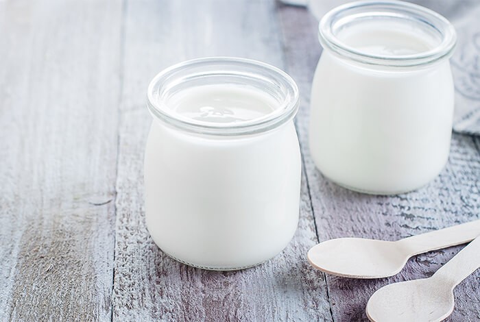 Two small glass jars of plain yogurt.