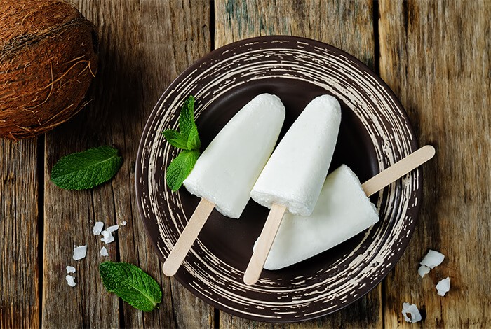 Three coconut yogurt ice pops on a brown ceramic plate.