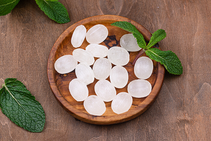 Peppermint candies displayed in a wooden plate.