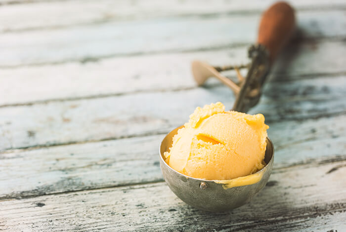 Yellow-colored dog ice cream on a scooper.