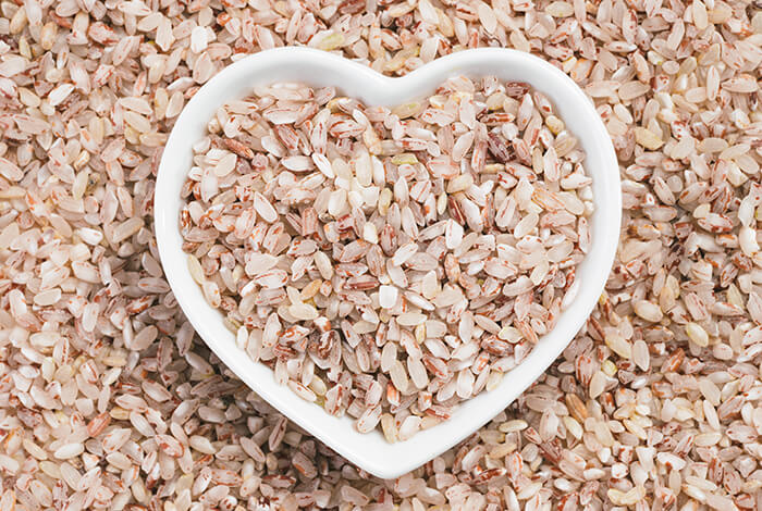 Uncooked red rice placed in a white heart-shaped bowl.